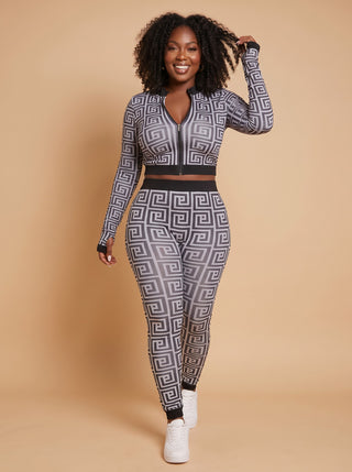 Model walking in a Greek key print two-piece set with a zip-front long-sleeve crop top and matching leggings
