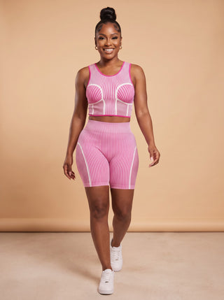 Model walking in a pink and white seamless crop tank and matching biker shorts set