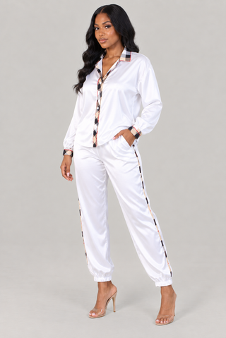 Front view-Woman in ivory satin button-front shirt and matching drawstring pants with tan and black check contrast trim, styled with clear heels